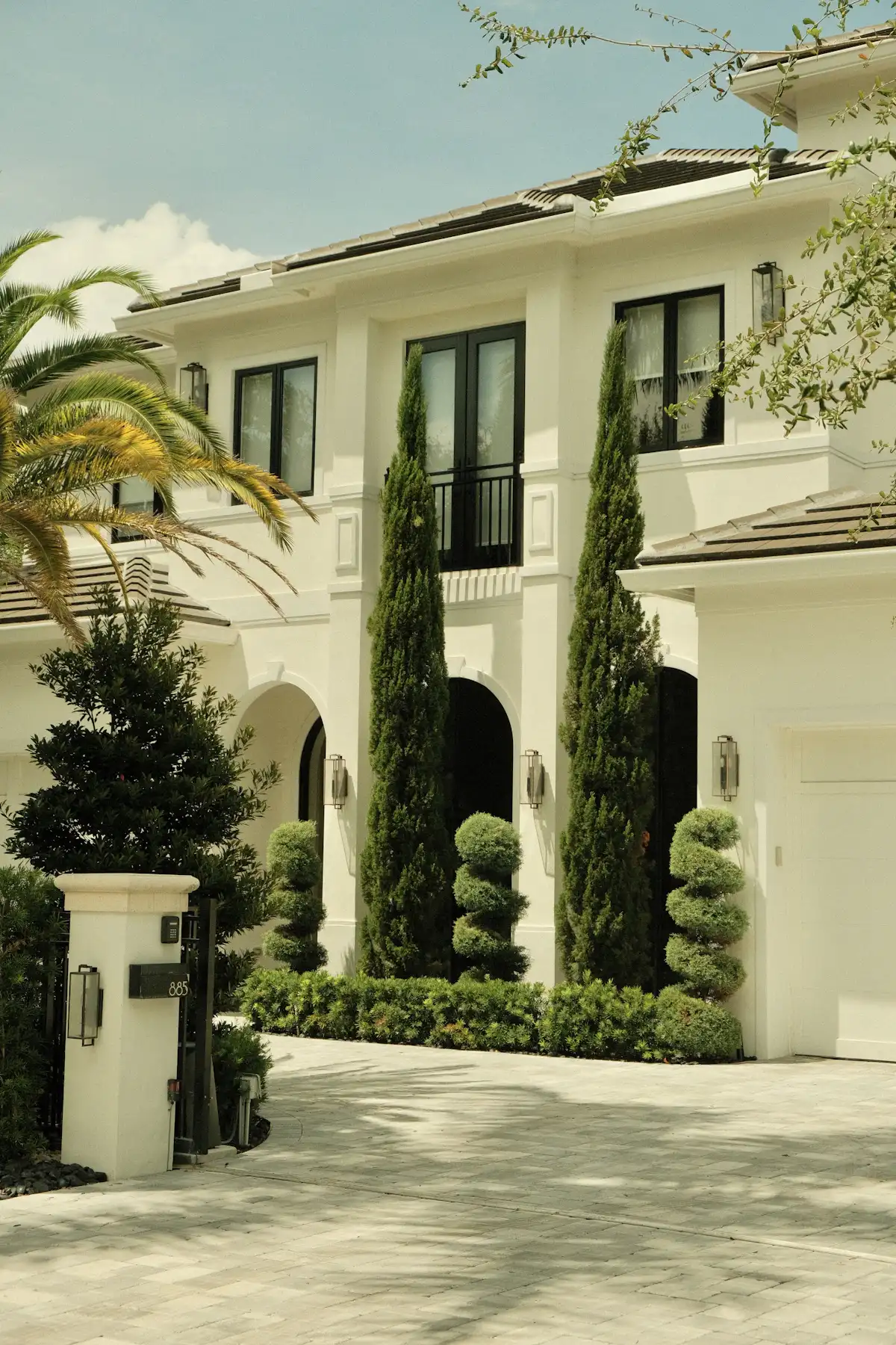 A white Mediterranean home with manicured topiaries